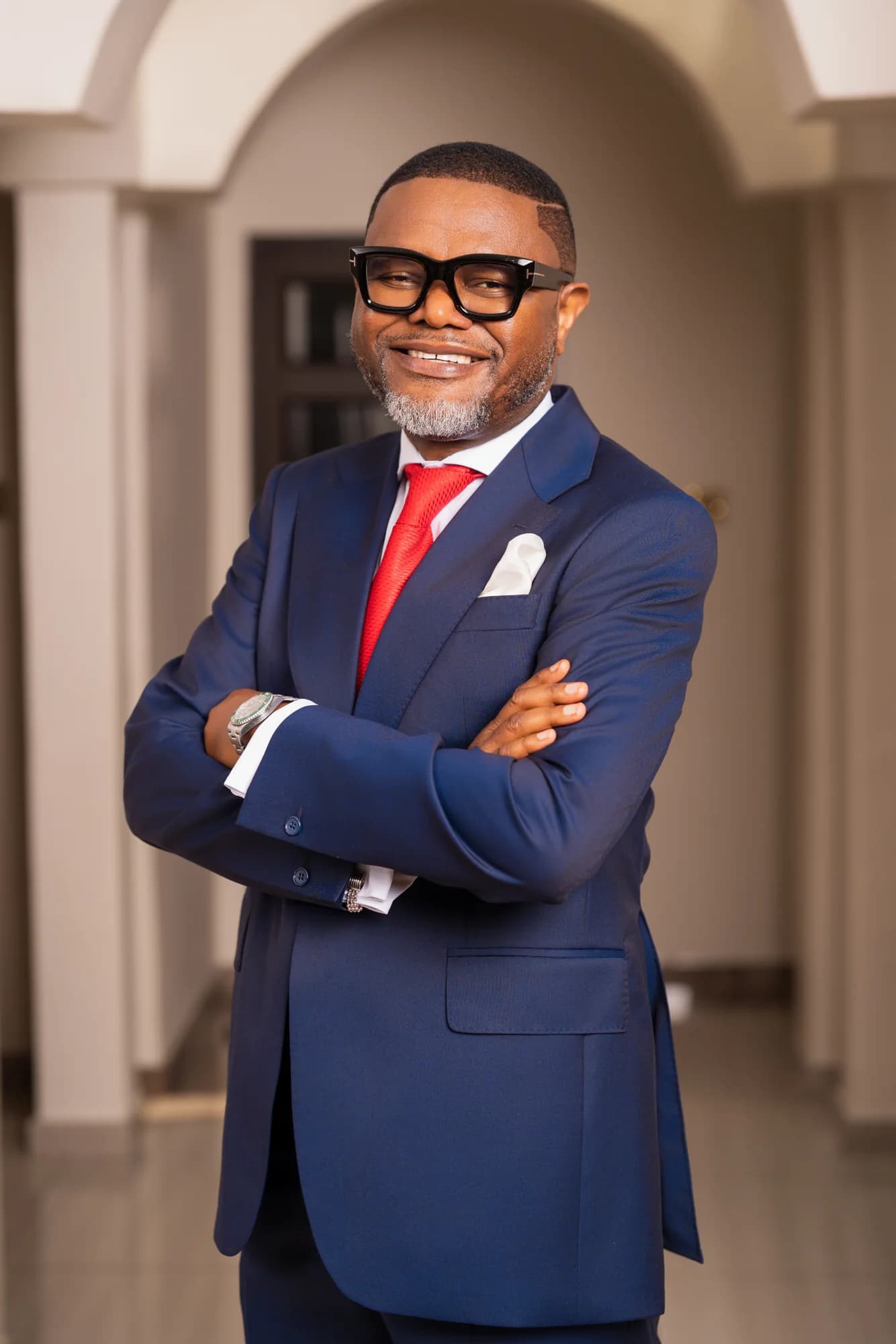 Bena Nkhoma with arms crossed in a navy suit